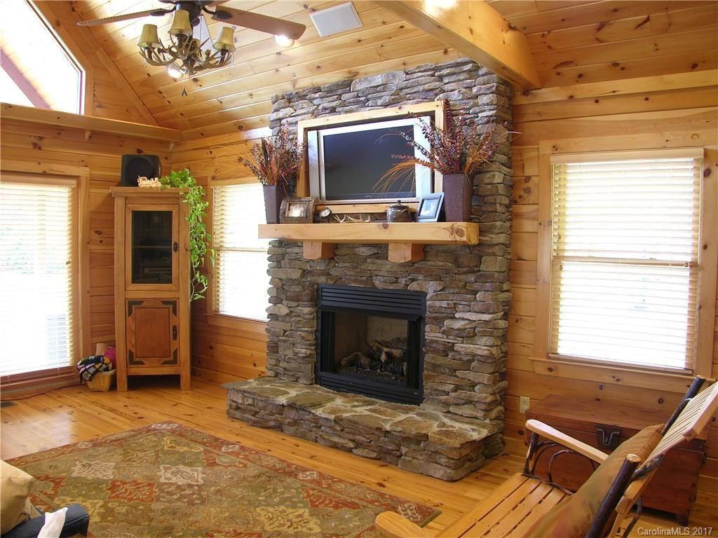 145 Spring Hill Ln Mill Spring, Unit 32 Mill Spring, NC 28756 - Photo 6 of 24 a living room with a fireplace a flat screen tv and windows