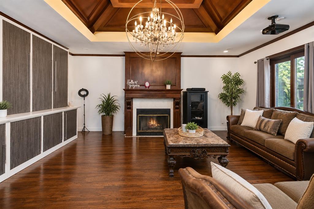 10505 Ferguson Road Dallas, TX 75228 - Photo 7 of 14 Spacious living area featuring rich wood-finish flooring, a wood-paneled tray ceiling, and a fireplace with a detailed wood mantel