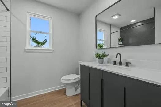 a bathroom with a granite countertop toilet sink and mirror