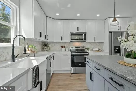 a kitchen with kitchen island granite countertop a sink stainless steel appliances and white cabinets