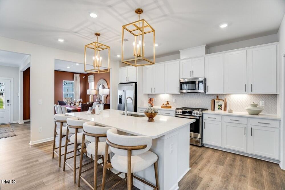 717 Bolera Road Knightdale, NC 27545 - Photo 14 of 43 a kitchen with stainless steel appliances a stove a sink a stove a refrigerator cabinets and chairs