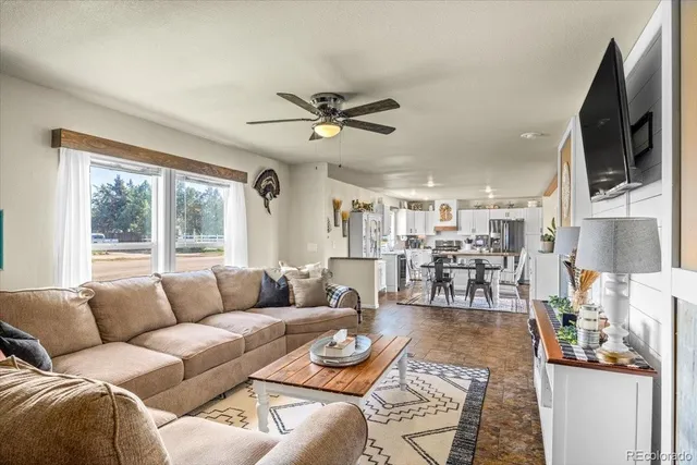 a living room with furniture a flat screen tv and a large window
