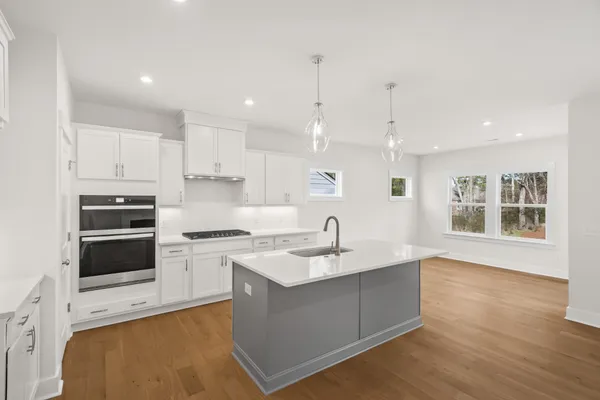 a large kitchen with stainless steel appliances granite countertop a sink a stove and a refrigerator