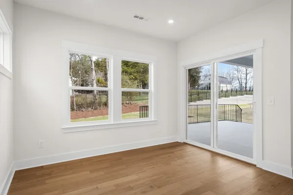 an empty room with wooden floor and windows