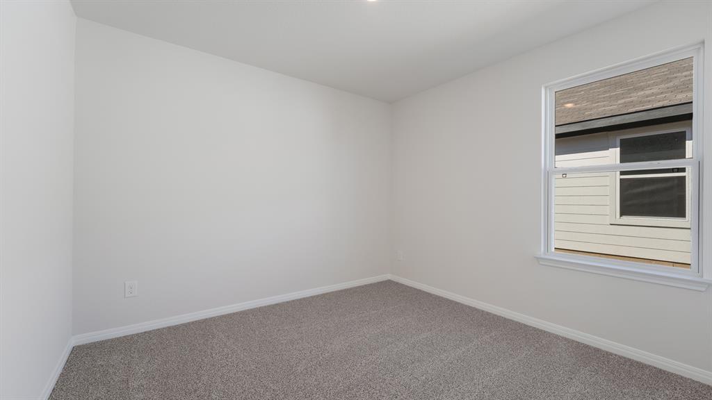 14021 Feinstein Street Manor, TX 78653 - Photo 19 of 25 A well-lit, neutral-toned room awaits personalization with its plush carpeting and large window.