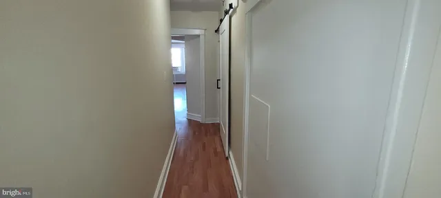 a view of a hallway with wooden floor and a bathroom