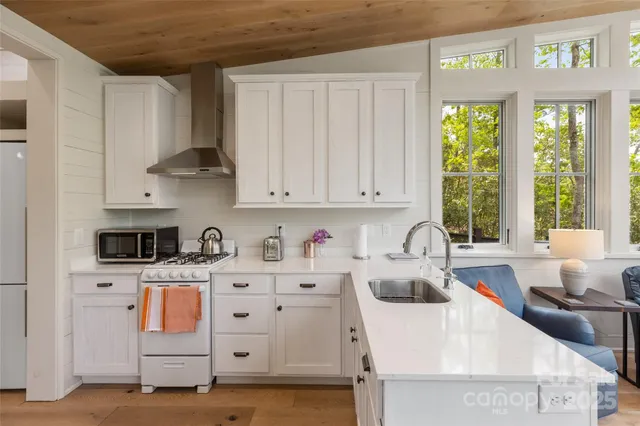 a kitchen with stainless steel appliances granite countertop a sink a stove and a wooden cabinets