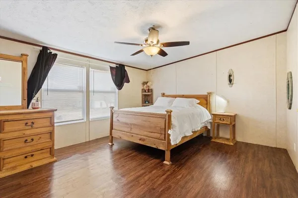 a bedroom with a bed and a dresser with wooden floor