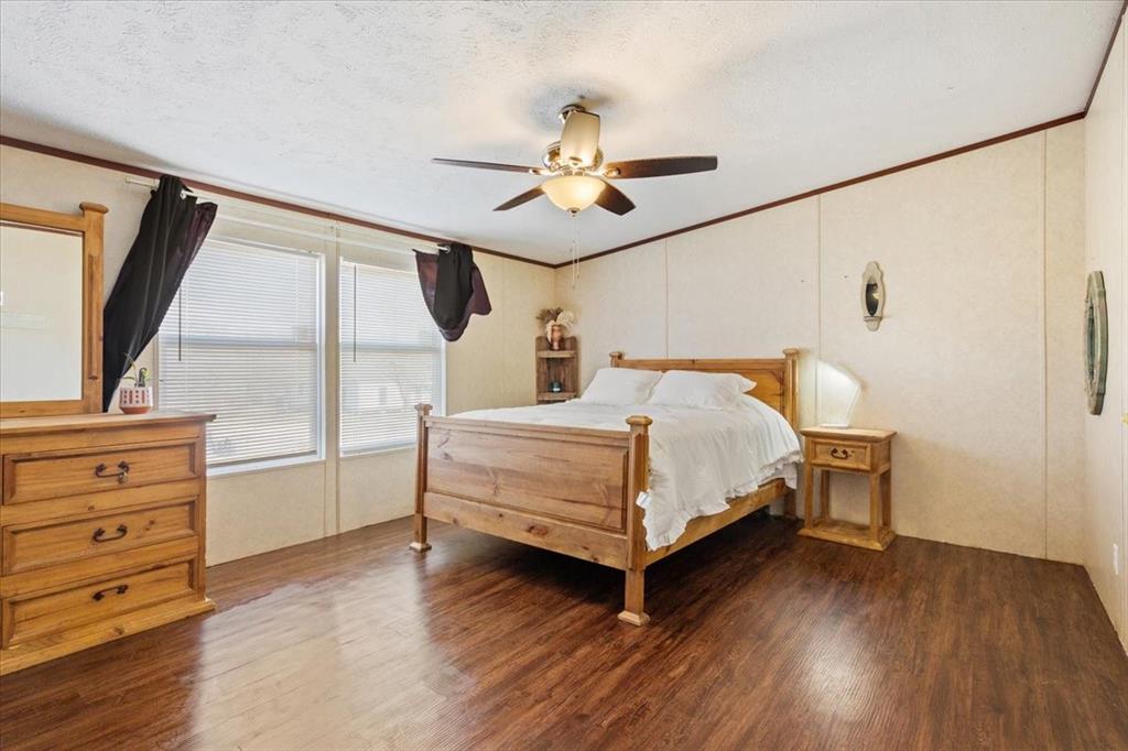 247 North Lake Street Axtell, TX 76624 - Photo 13 of 24 a bedroom with a bed and a dresser with wooden floor