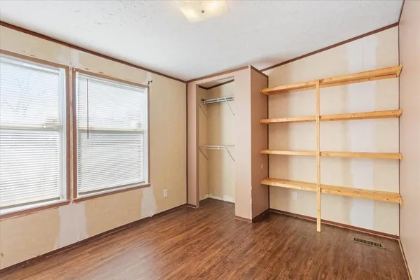 a view of an empty room with a window and wooden floor