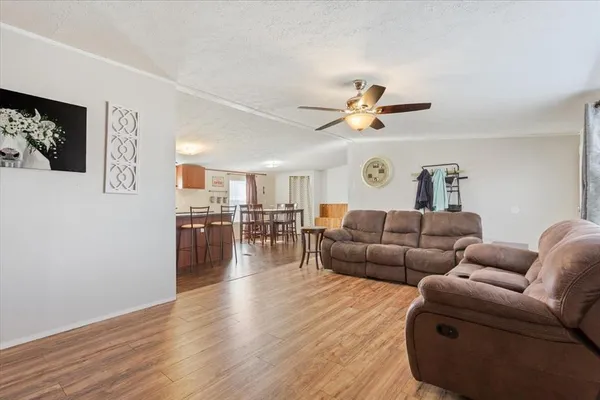 a living room with furniture wooden floor and a ceiling fan