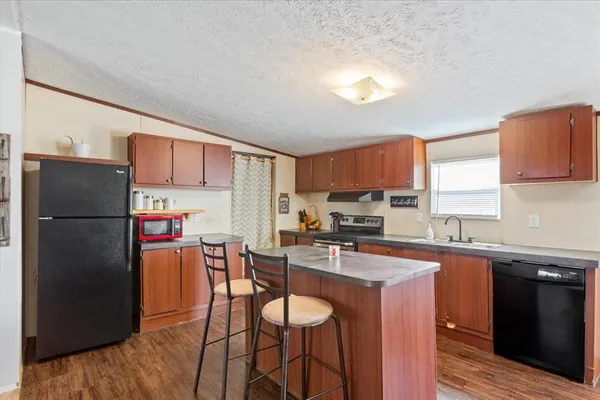 a kitchen with stainless steel appliances granite countertop a refrigerator a sink a stove a dining table and chairs