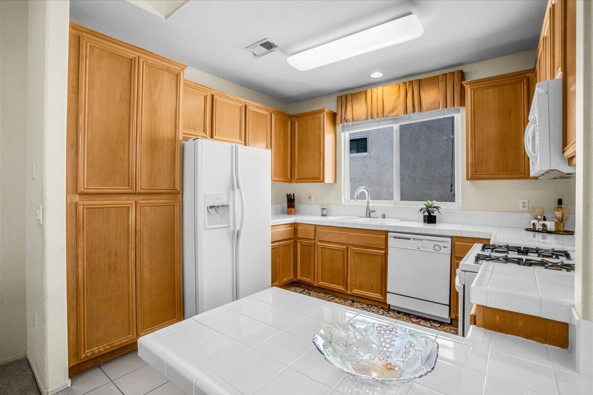 47795 Soft Moonlight La Quinta, CA 92253 - Photo 10 of 44 a kitchen with stainless steel appliances granite countertop a refrigerator a sink dishwasher and wooden cabinets with wooden floor