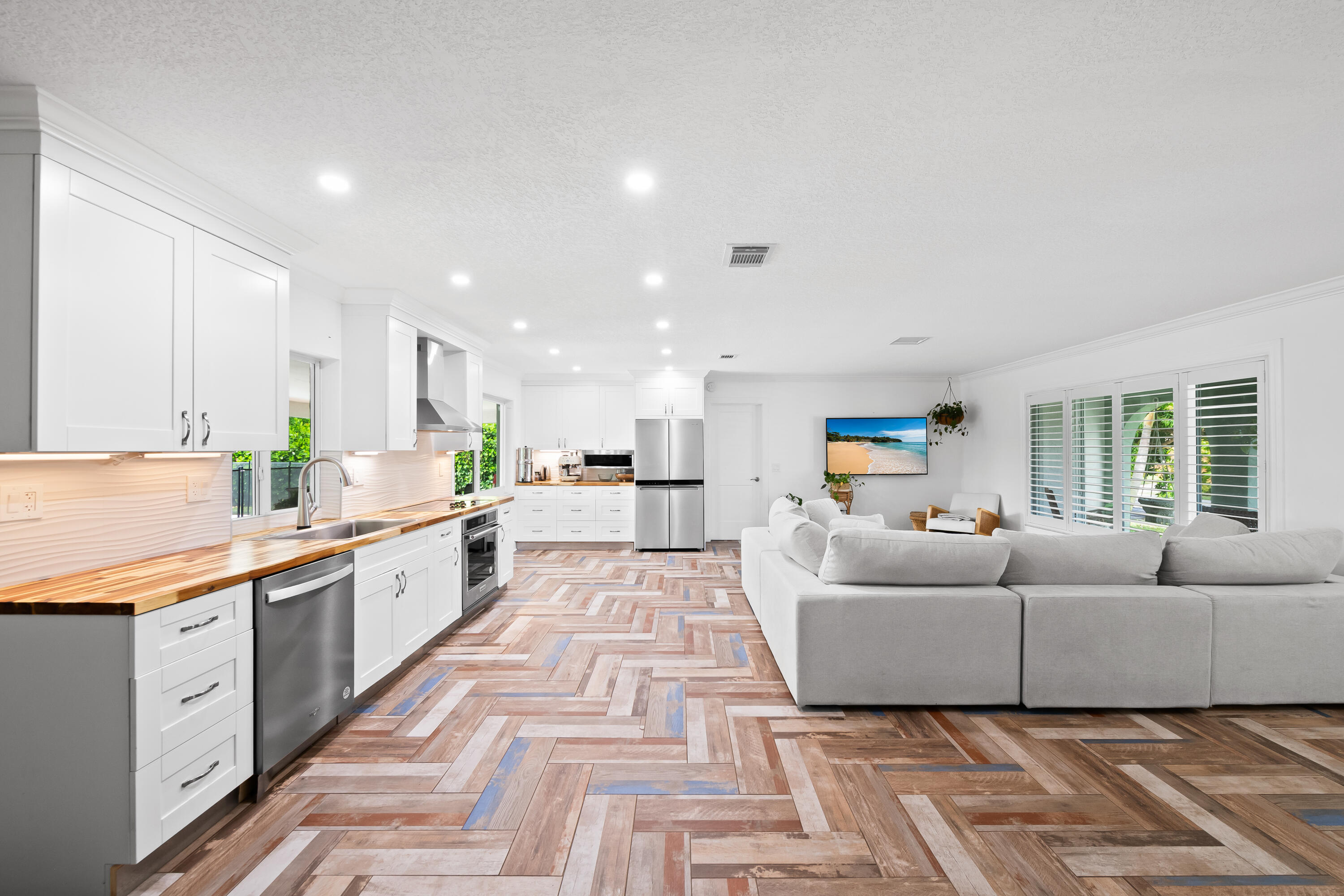 3333 Northwest 26th Court Boca Raton, FL 33434 - Photo 3 of 41 a large white kitchen with stainless steel appliances granite countertop a couch and a view of living room