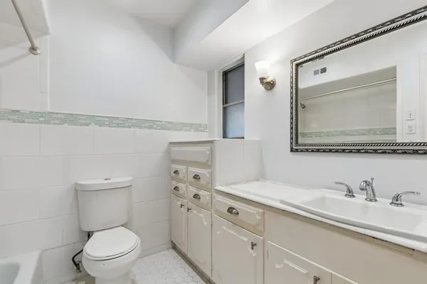 a bathroom with a granite countertop toilet sink and mirror