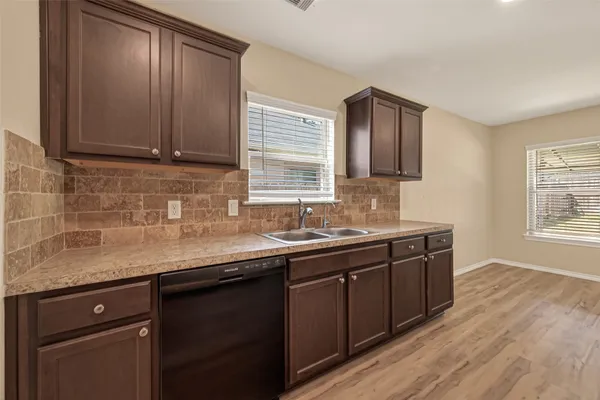 a kitchen with stainless steel appliances granite countertop wooden cabinets a sink and dishwasher with wooden floor