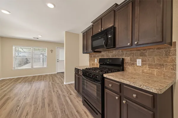 a kitchen with granite countertop wooden cabinets and a stove top oven
