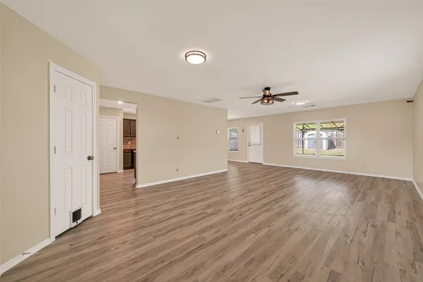 an empty room with wooden floor cabinet and windows