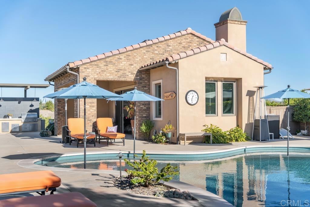 15433 Artesian Ridge San Diego, CA 92127 - Photo 9 of 20 a view of a white house with a yard and table and chairs under an umbrella
