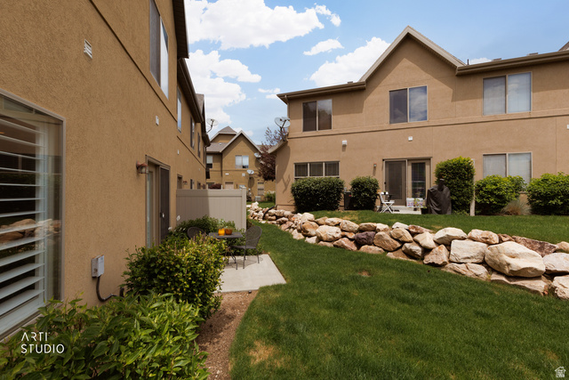 6761 950 East Midvale, UT 84047 - Photo 28 of 44 Rear exterior featuring a rock retaining wall, mature landscaping, and a patio with direct access to the interior