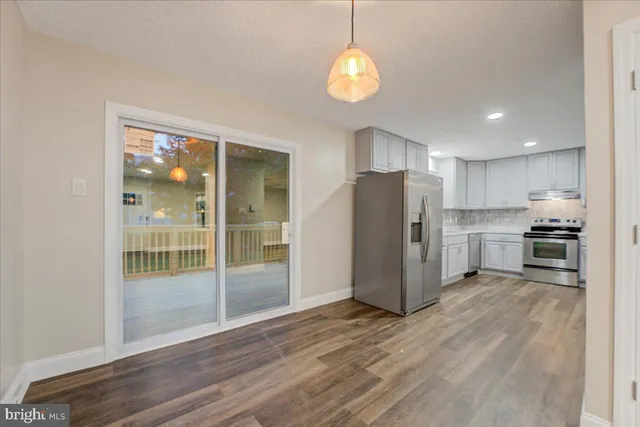 a view of kitchen with refrigerator cabinets and wooden floor