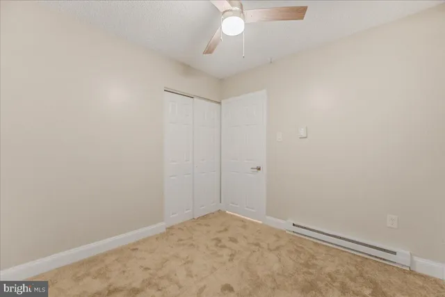 an empty room with a ceiling fan and carpet