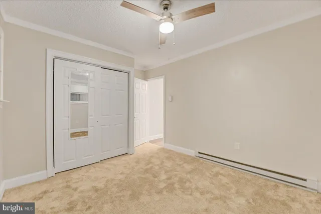 an empty room with closet and a ceiling fan