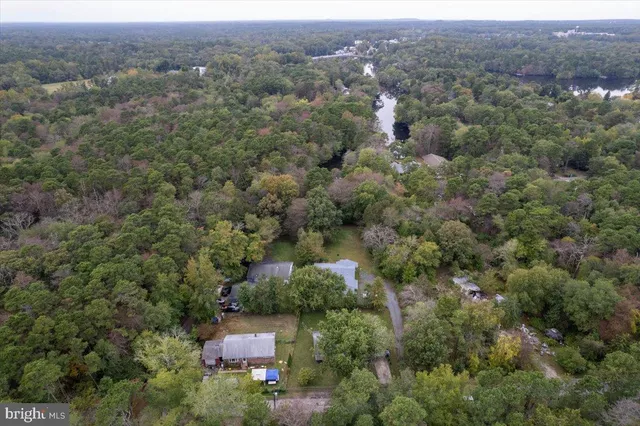 an aerial view of residential house with outdoor space and trees all around