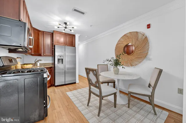 a kitchen with stainless steel appliances granite countertop a refrigerator a stove a sink dishwasher and a dining table with wooden floor