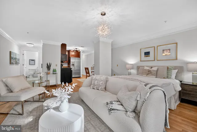 a bedroom with a bed couches chair and three large windows