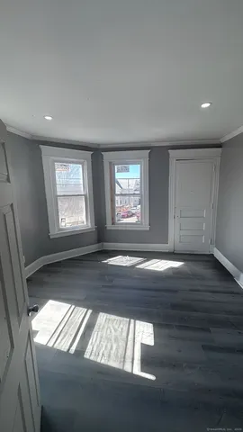 a view of an empty room with wooden floor and window
