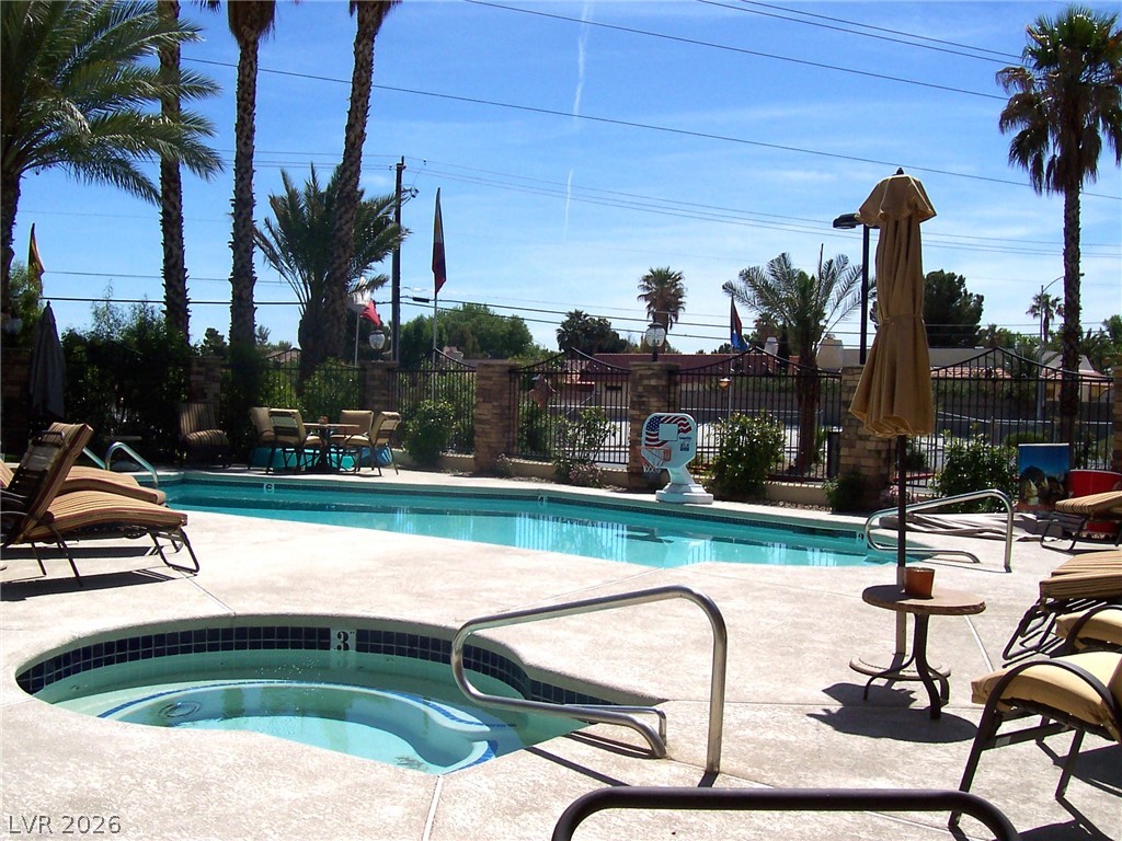 3135 South Mojave Road, Unit 221 Las Vegas, NV 89121 - Photo 18 of 19 A refreshing pool and spa invite relaxation under the desert sun, surrounded by palm trees.