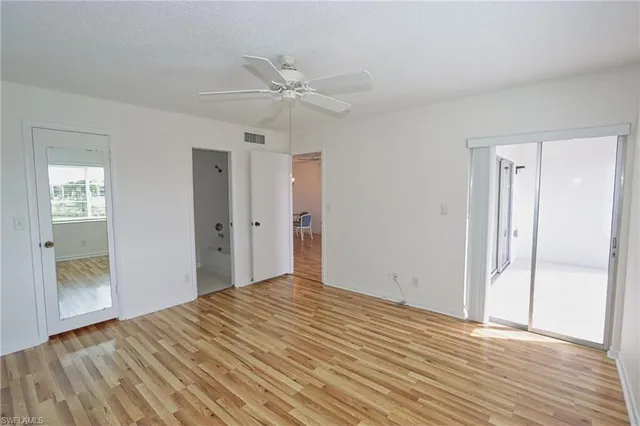 a view of empty room with wooden floor and fan