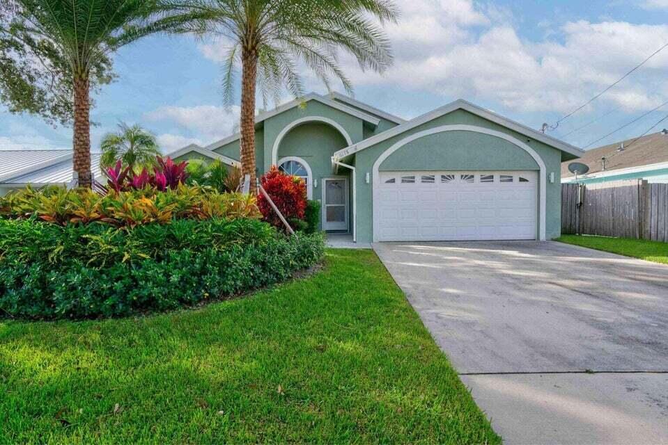 6178 Garrett Street Jupiter, FL 33458 - Photo 1 of 18 a front view of a house with garden