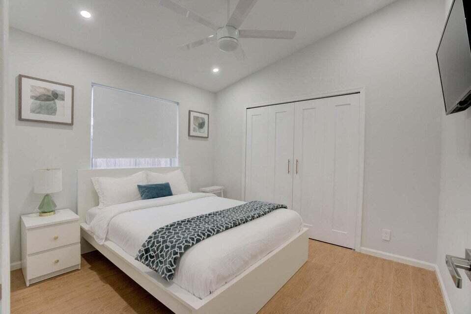 6178 Garrett Street Jupiter, FL 33458 - Photo 14 of 18 a bedroom with a white bed and a chandelier