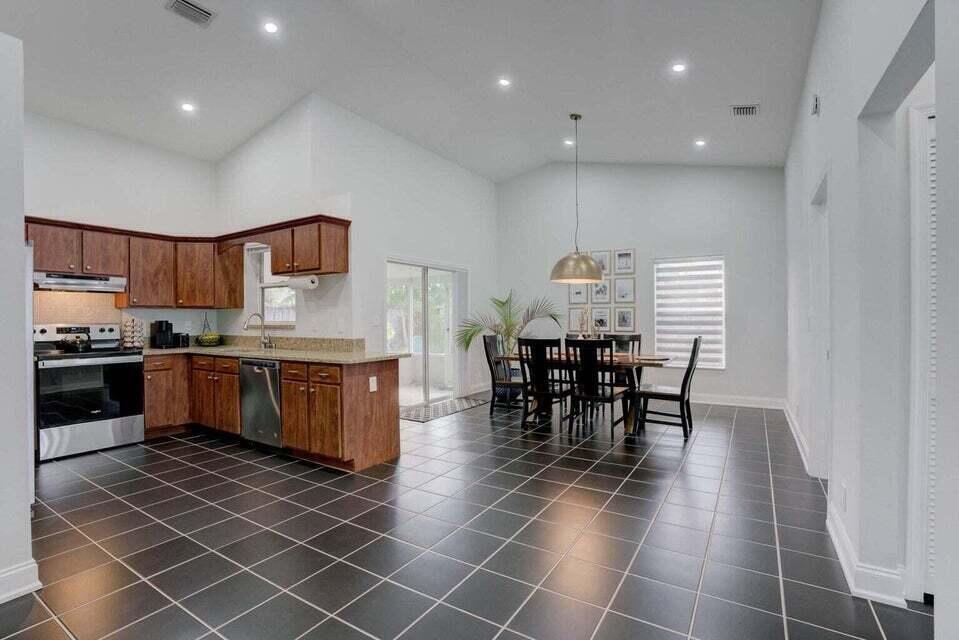 6178 Garrett Street Jupiter, FL 33458 - Photo 7 of 18 a kitchen with stainless steel appliances a sink a stove a microwave a dining table and chairs