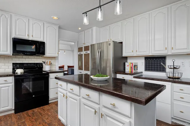 a kitchen with granite countertop stainless steel appliances a sink a stove and cabinets