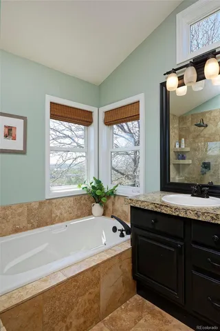 a bathroom with a granite countertop tub sink and mirror