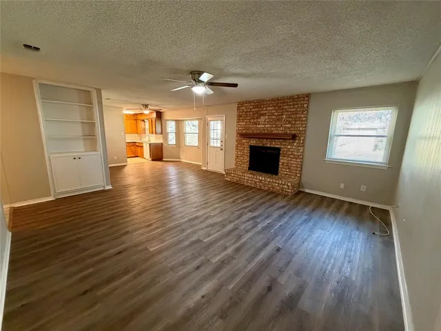 an empty room with wooden floor fireplace and windows