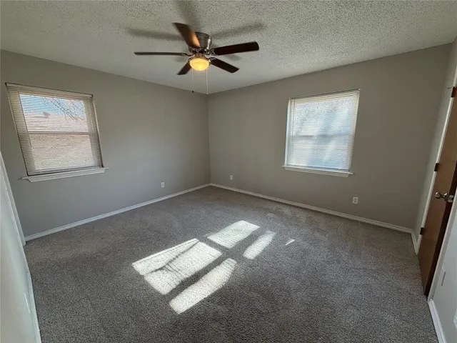an empty room with windows and fan