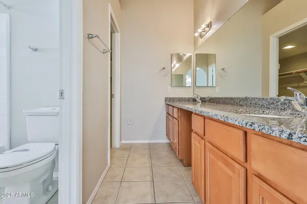 a bathroom with a granite countertop sink a toilet and a mirror