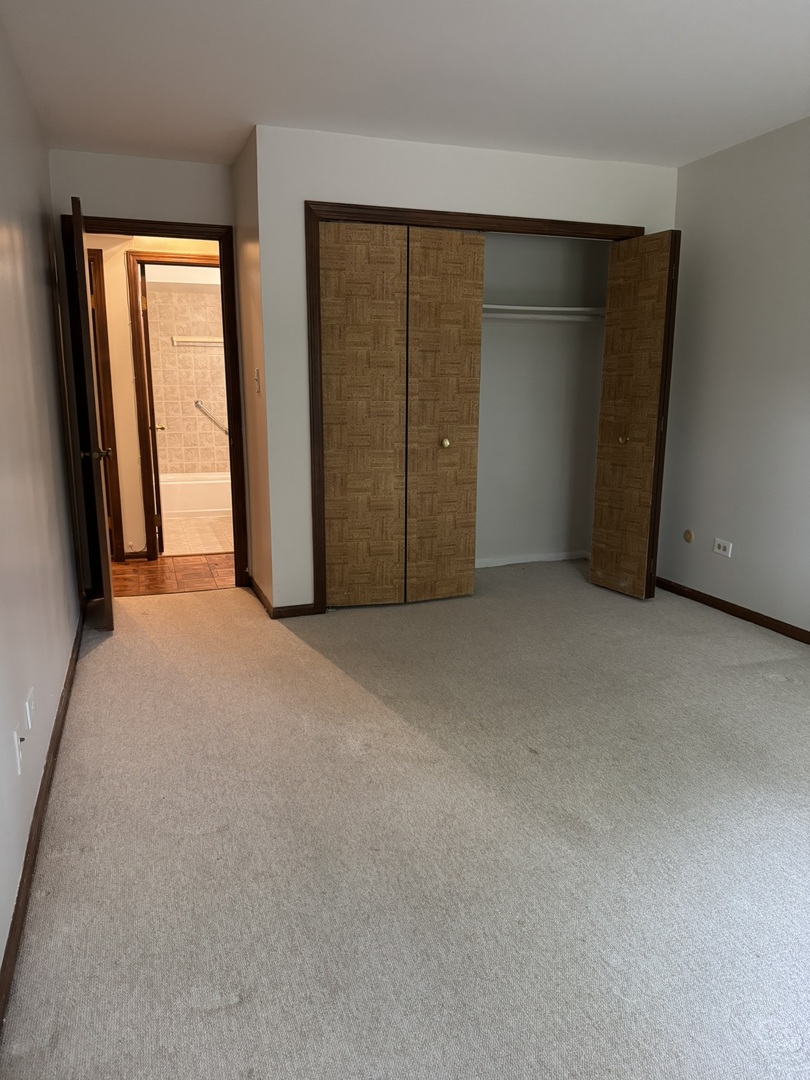 9244 Gross Point Road, Unit 103 Skokie, IL 60077 - Photo 14 of 28 an empty room with closet and sliding door