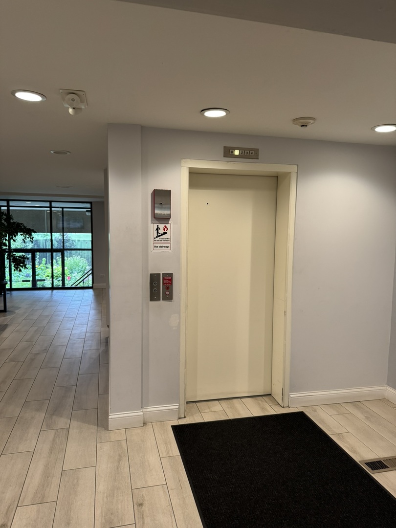 9244 Gross Point Road, Unit 103 Skokie, IL 60077 - Photo 3 of 28 an empty room with wooden floor and windows