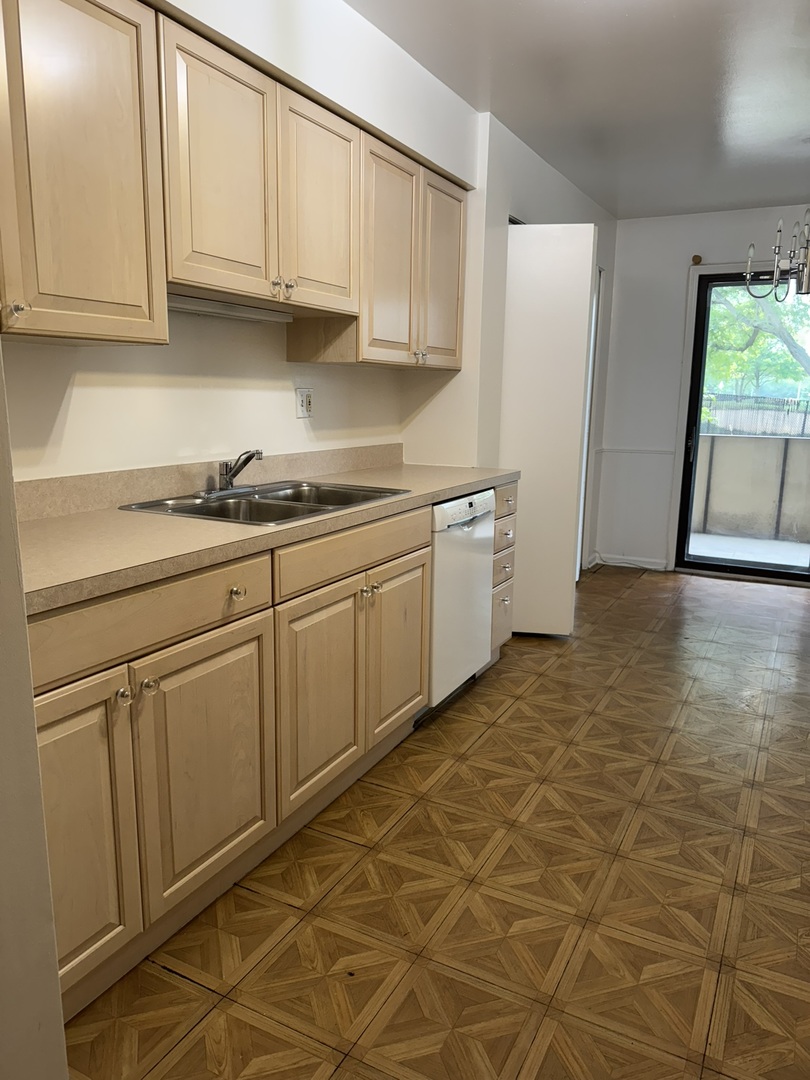 9244 Gross Point Road, Unit 103 Skokie, IL 60077 - Photo 7 of 28 a kitchen with stainless steel appliances granite countertop a sink and cabinets
