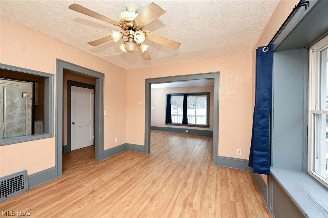 77 West Mildred Avenue Akron, OH 44310 - Photo 11 of 40 Unfurnished room featuring light wood-style floors, a textured ceiling, and a ceiling fan