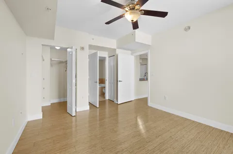an empty room with wooden floor and ceiling fan
