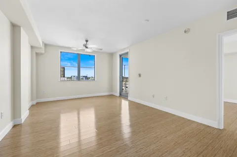 a view of empty room with wooden floor and fan