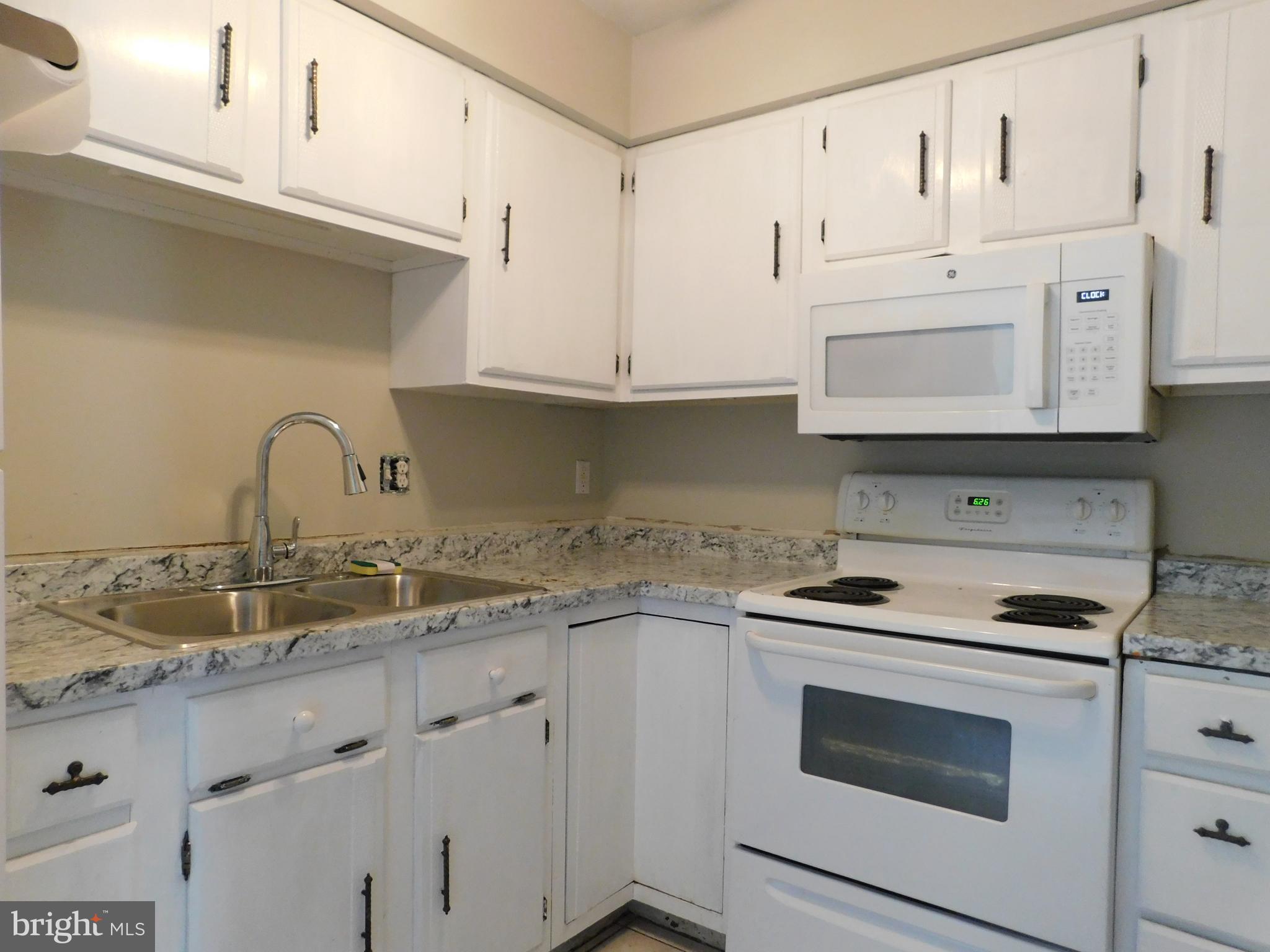 221 East Fairfax Street Berryville, VA 22611 - Photo 10 of 15 a kitchen with granite countertop white cabinets and white appliances