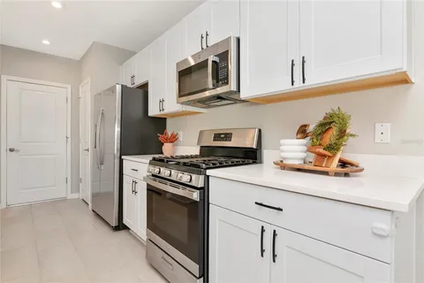 a kitchen with stainless steel appliances kitchen island granite countertop a dining table chairs and a refrigerator