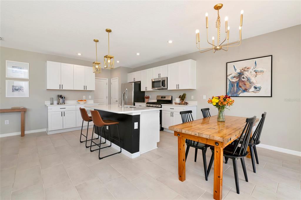 6283 Springmont Loop Palmetto, FL 34221 - Photo 22 of 68 a kitchen with stainless steel appliances kitchen island granite countertop a dining table chairs and a refrigerator